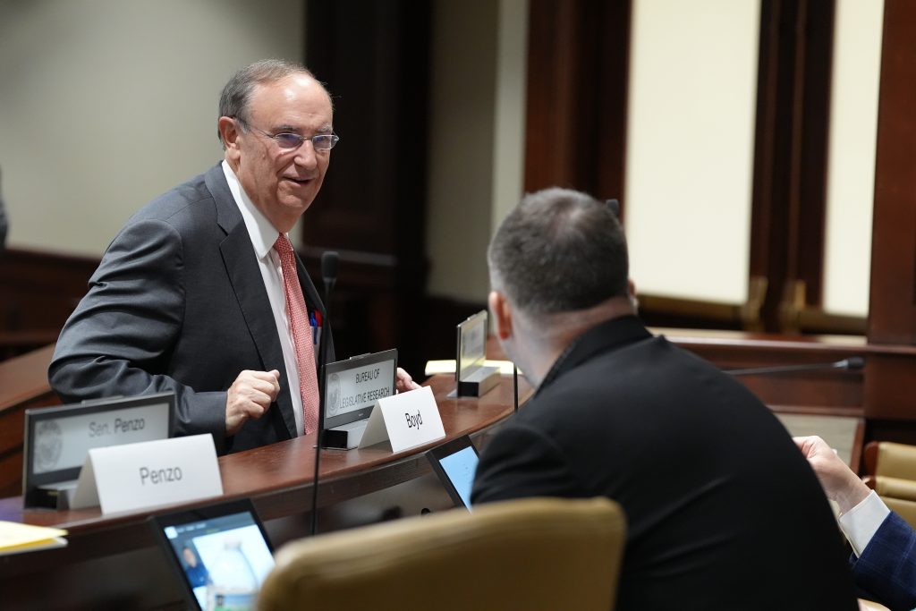 Senator Mark Johnson talks with Senator Clint Penzo during a committee meeting in March 2026.