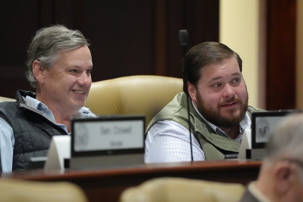 Senator Flippo smiles while listening in a committee meeting. Senator Gilmore is sitting beside him.