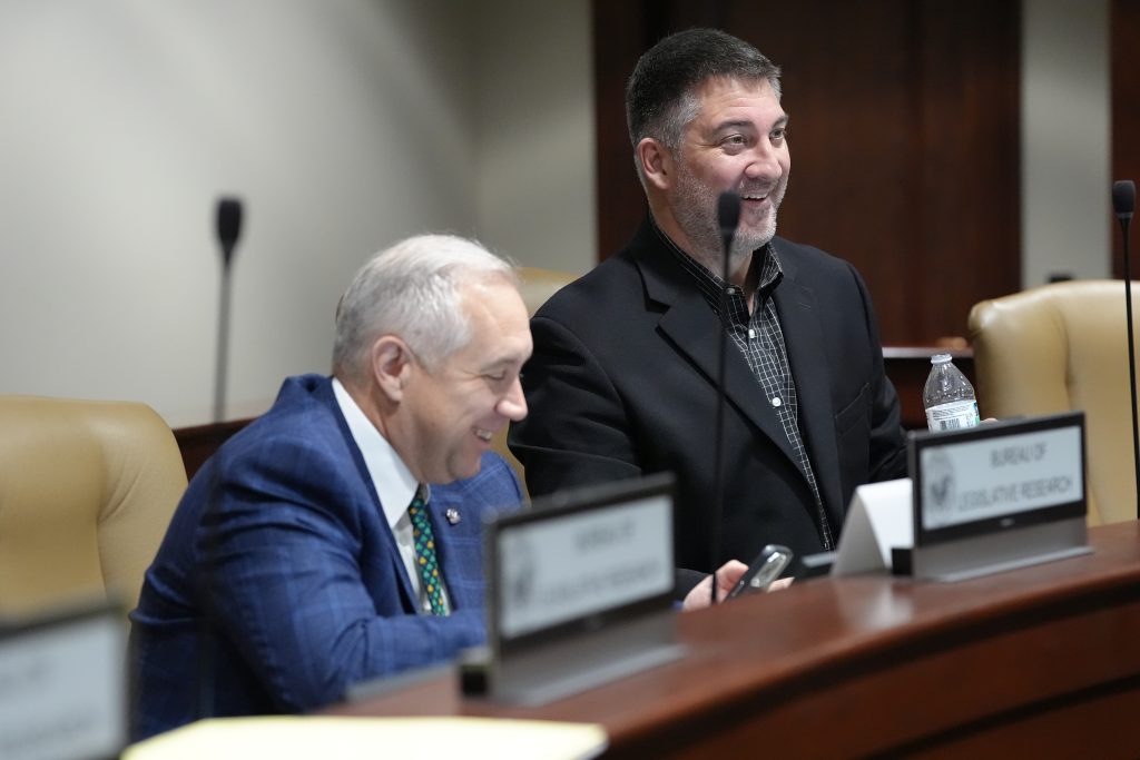 Senator Penzo smiles while talking to colleagues before a committee meeting