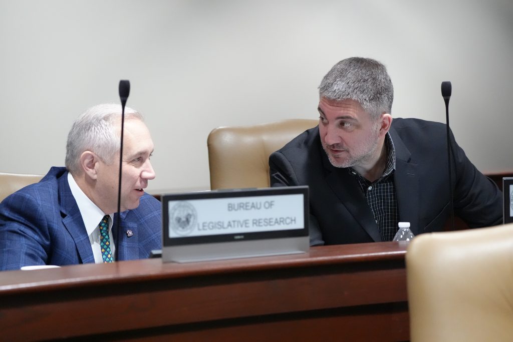 Senator Penzo talks with Senator Boyd in a committee room