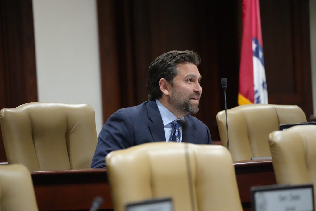 Senator Dismang smiles while talking with a colleague before a committee meeting.