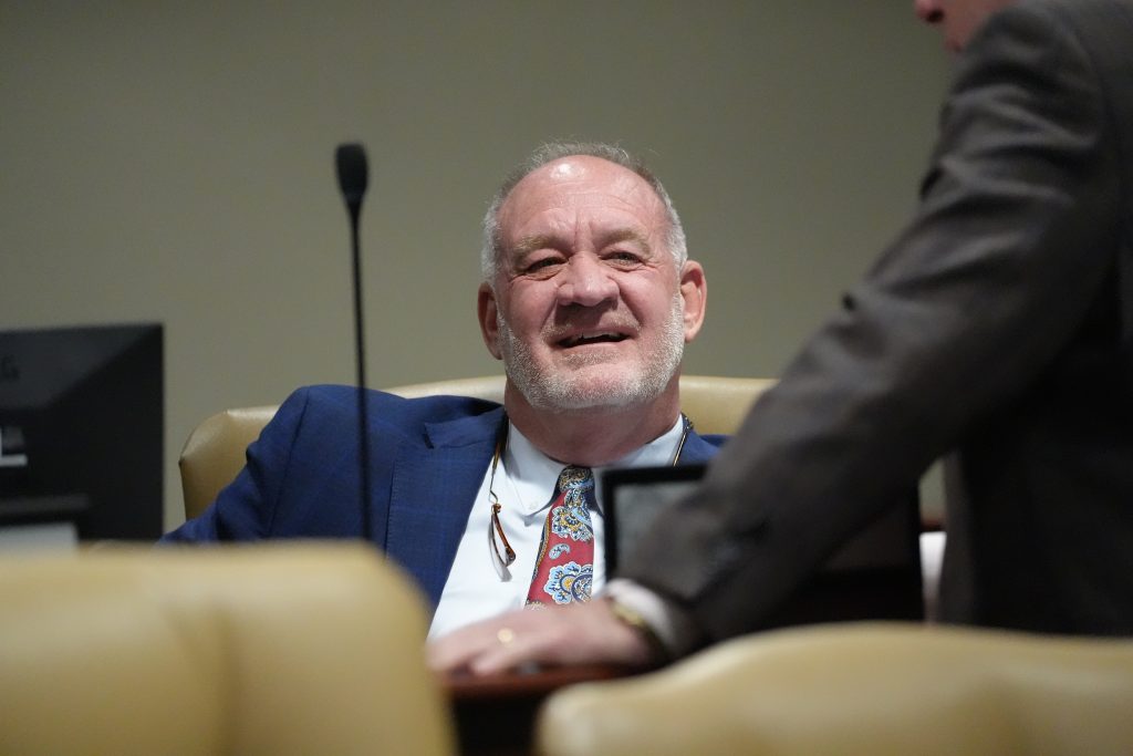 Senator Jimmy Hickey, Jr. smiles before a committee meeting while talking to a fellow senator.