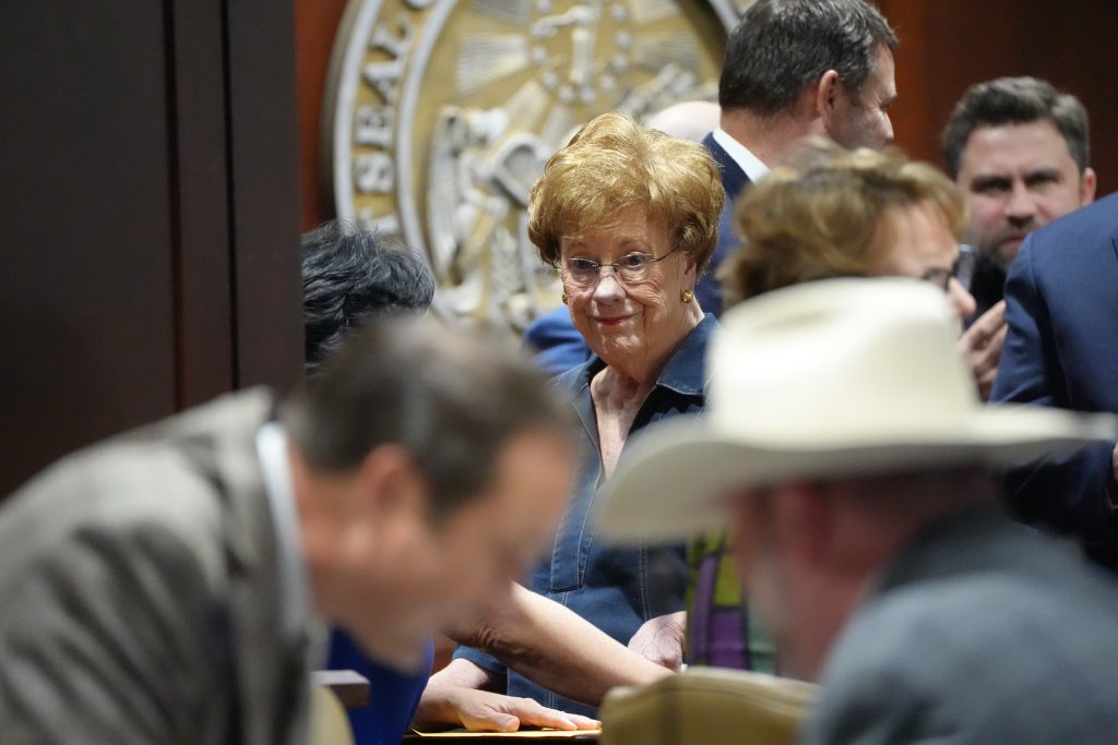 Senator English smiles while speaking with colleagues before a committee meeting