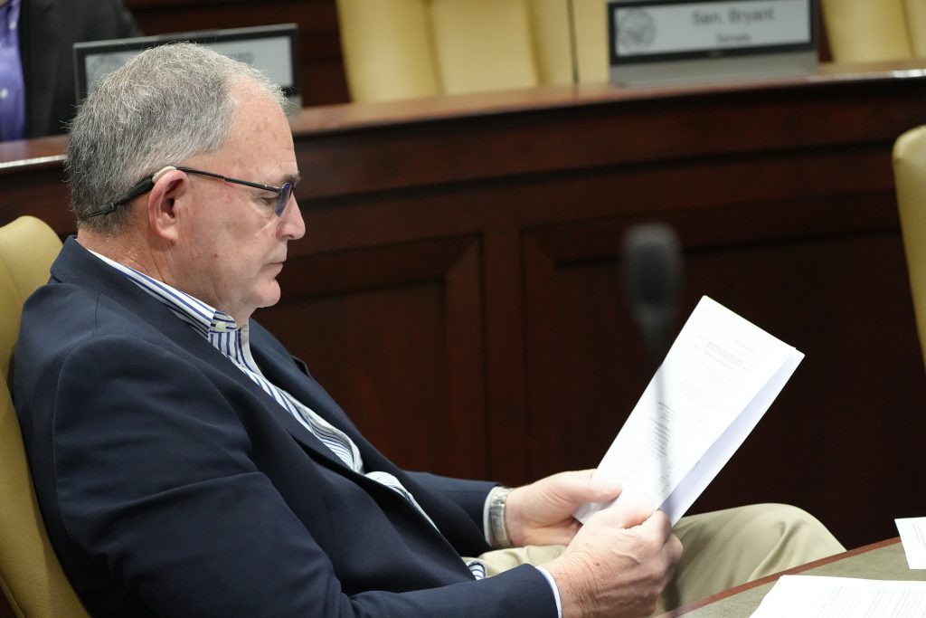Senator Stone reads a report before a committee meeting