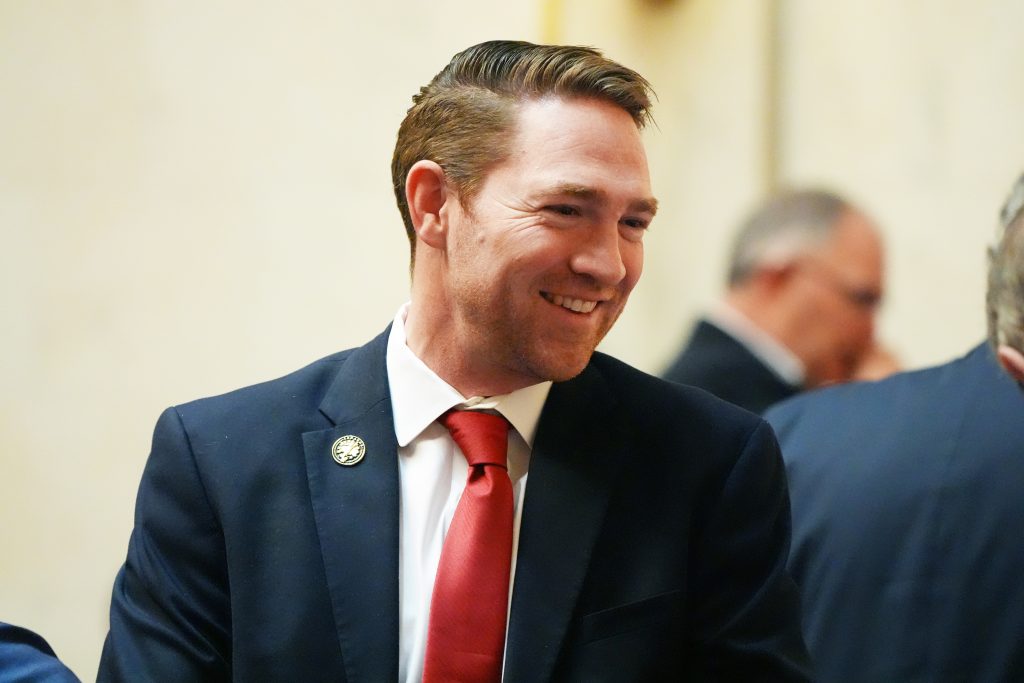 Senator Dees smiles while speaking with colleagues in the Senate chamber