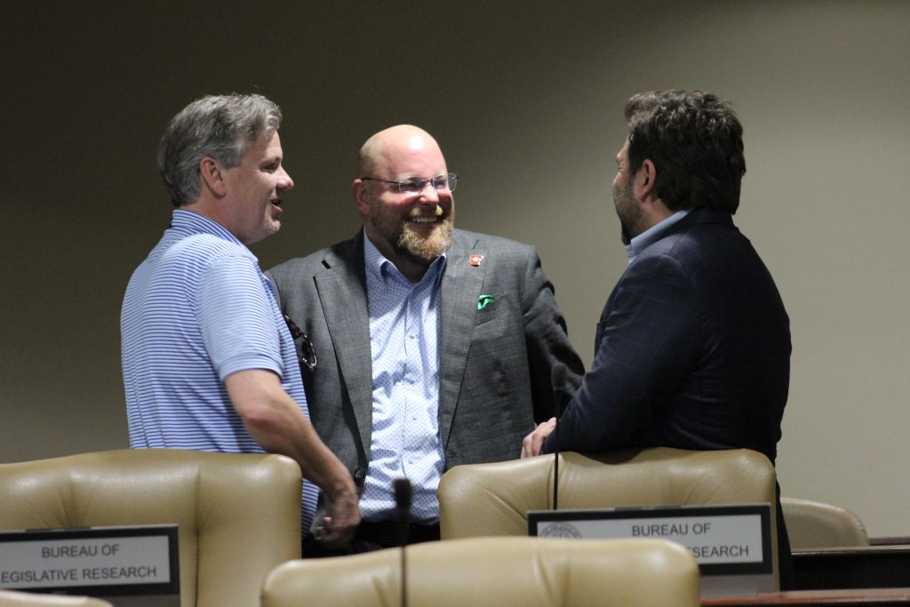 Senator Crowell talks and laughs with Senator Flippo and Senator Dismang after a committee meeting