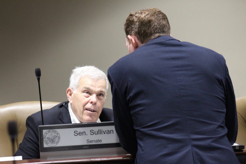 Senator Sullivan speaks with a colleague in a committee meeting