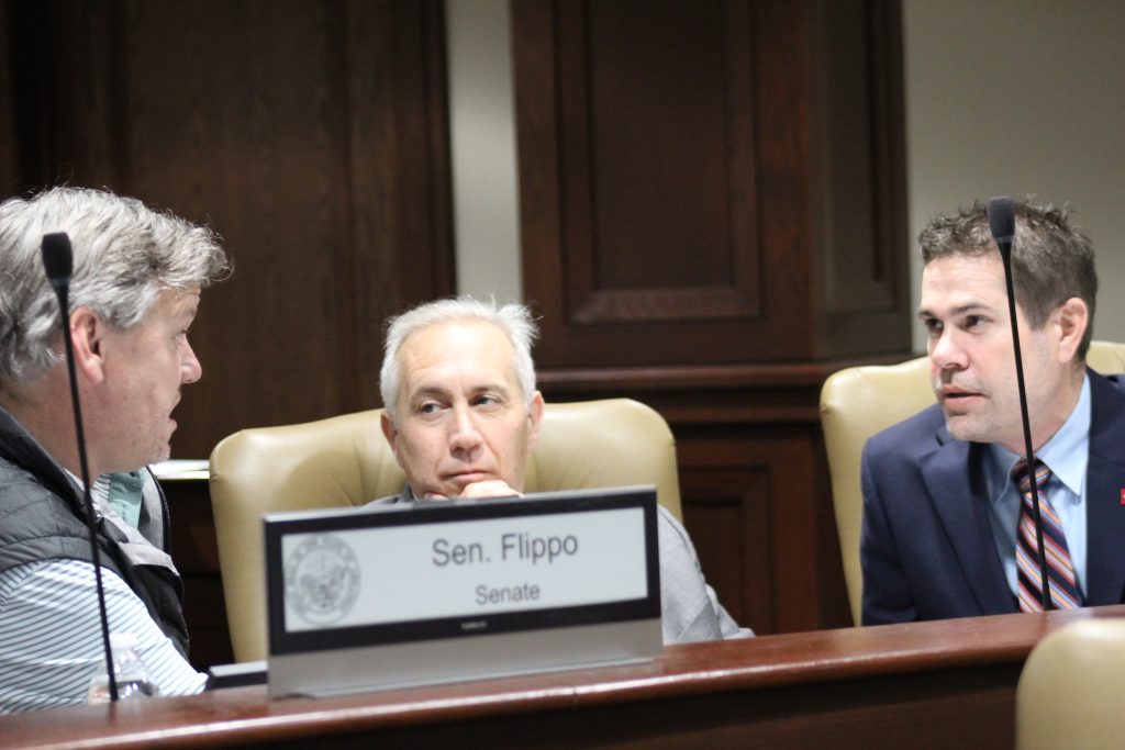 Senator Boyd listens as Senator Flippo and Senator Simon talk before a committee meeting.