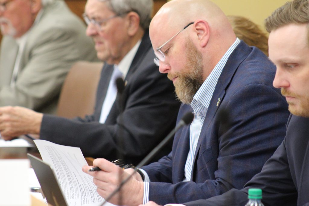 Senator Crowell reads a report in a committee meeting
