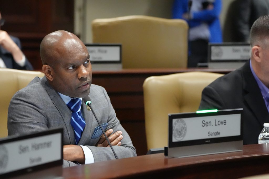 Senator Love speaks into a microphone in a committee room