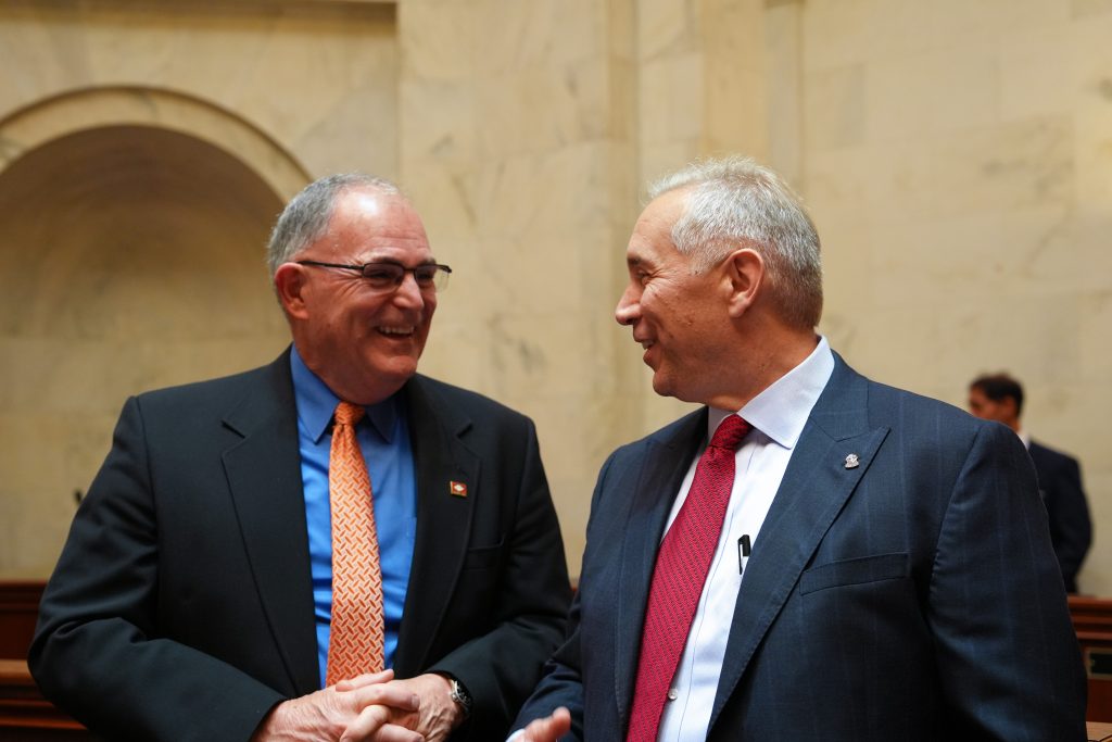 Senators Stone and Boyd smile while talking to each other in the Senate chamber.