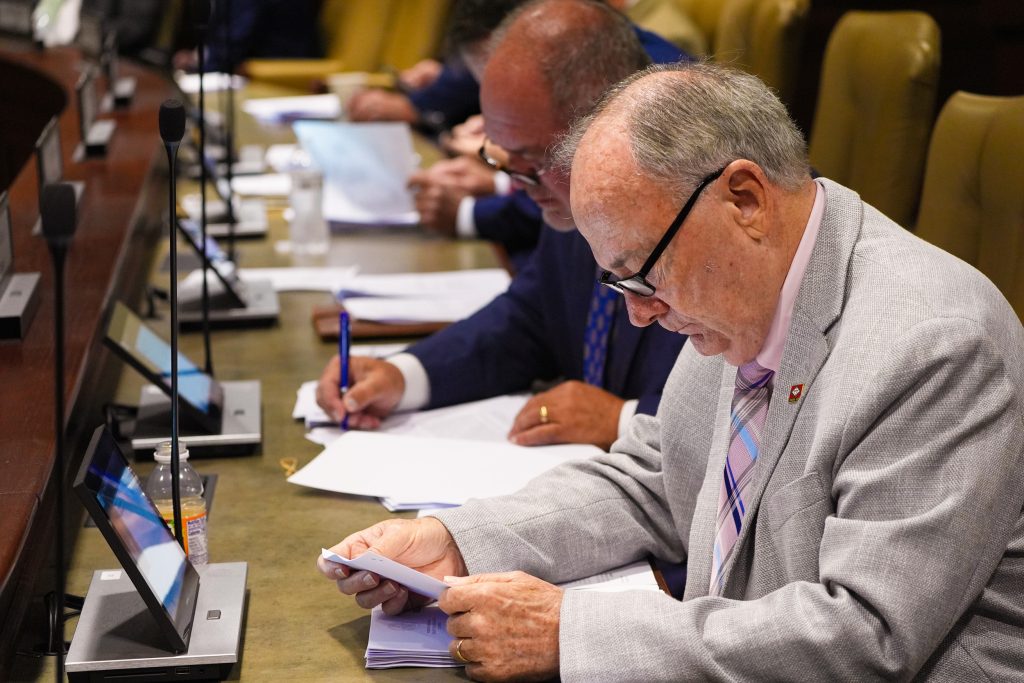 Senator Caldwell reads documents at his desk in a committee room