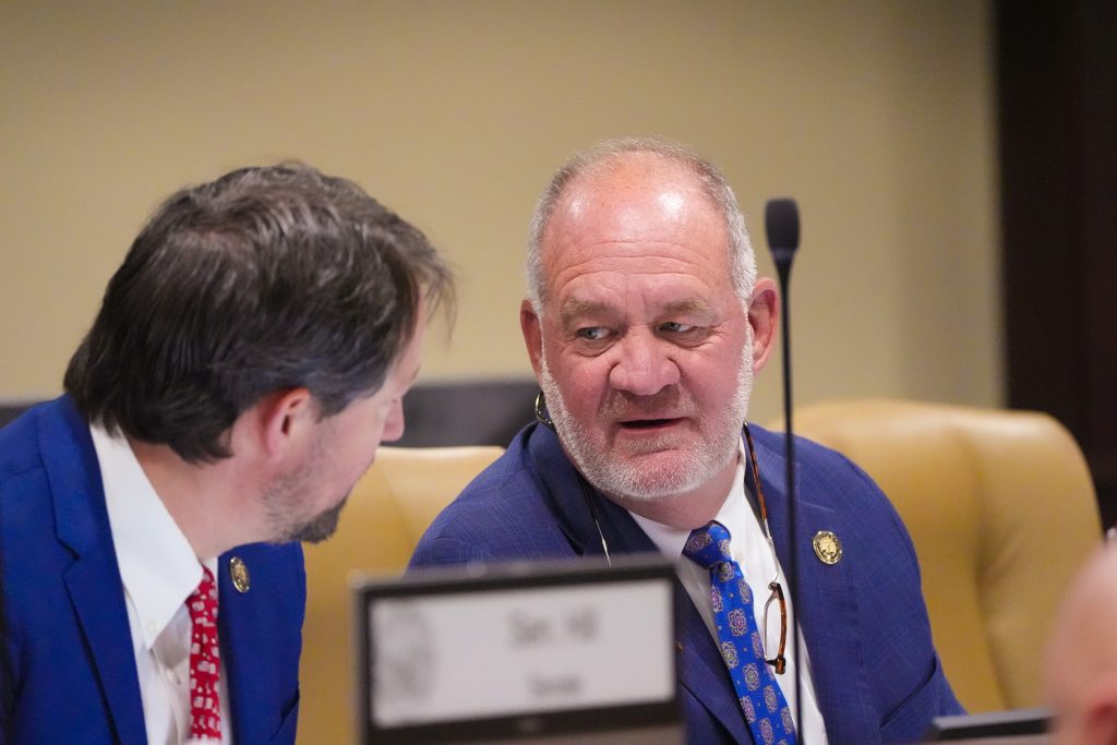 Senators Tucker and Hickey talk in a committee room