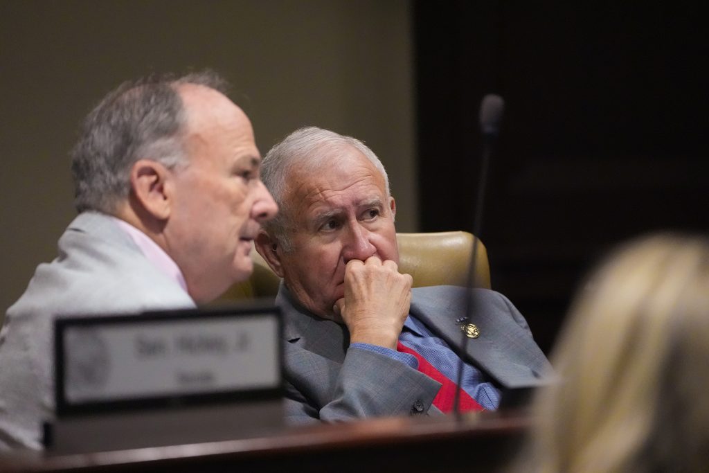 Senator Caldwell and Senator Wallace talk in a committee room