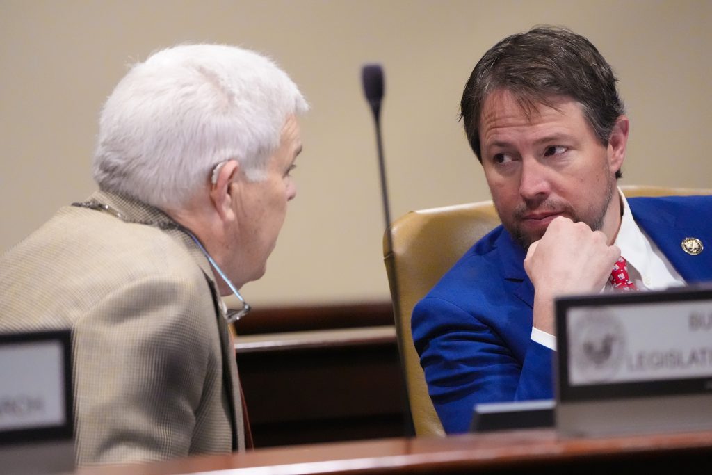 Senator Sullivan talks with Senator Tucker in a committee room