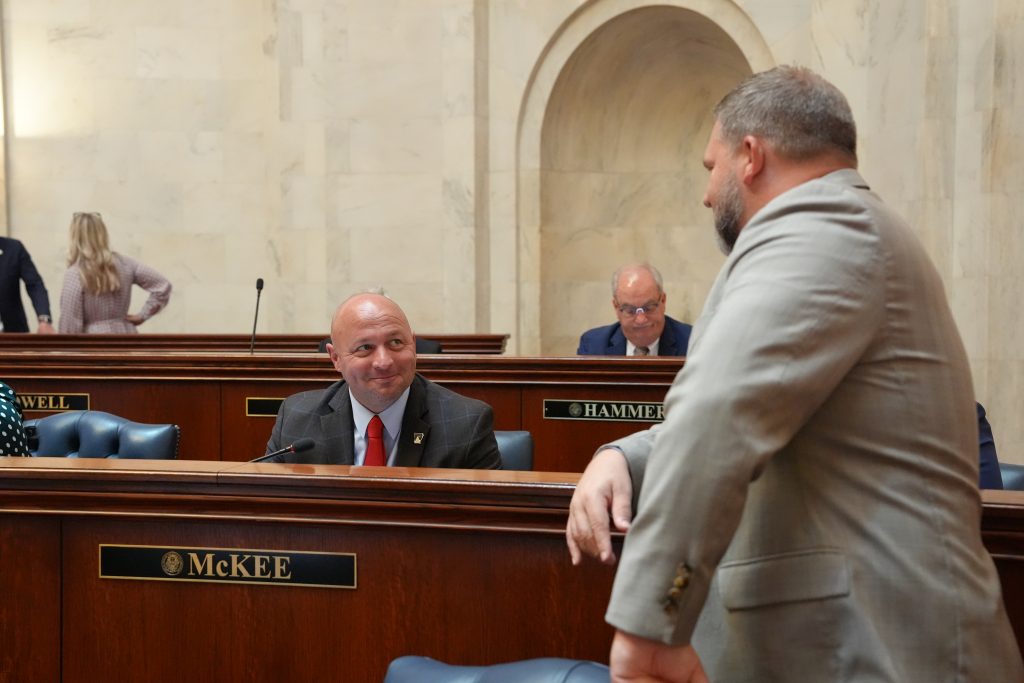 Senator McKee smiles while talking with Senator Dotson in the Senate chamber