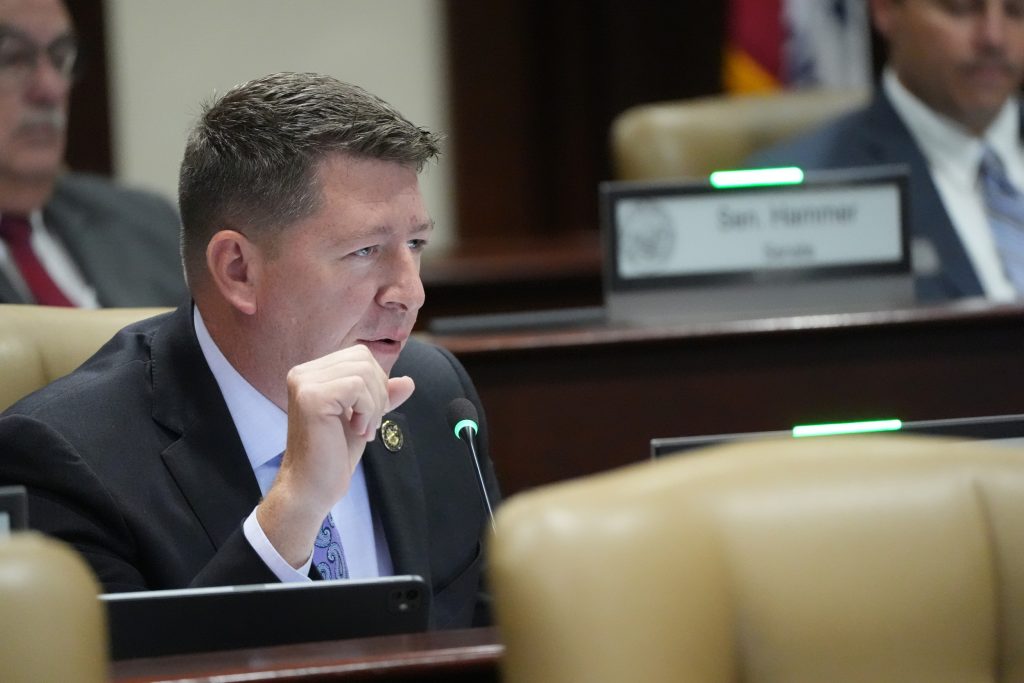 Senator Bryant talks into a microphone in a committee room