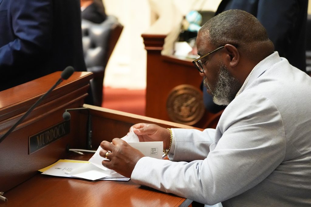 Senator Murdock reads some papers at his desk in the Senate chamber.