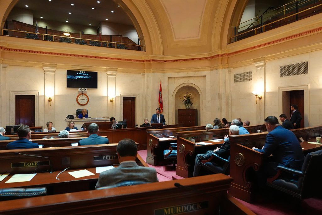Senator Tucker speaks before the Senate. You can see most of the chamber with senators listening from their desks.