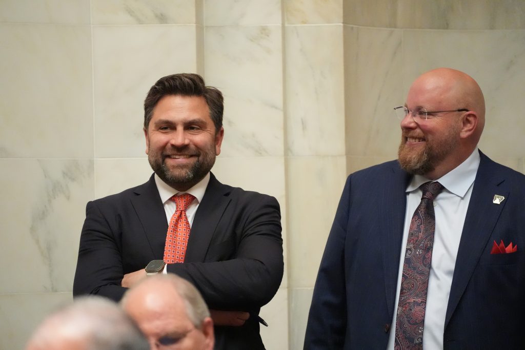 Senators Dismang and Crowell smile while standing next to each other in the Senate chamber.