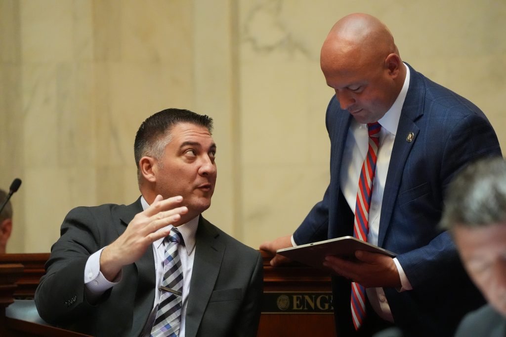 Senator Penzo gestures while talking to Senator McKee in the Senate chamber.
