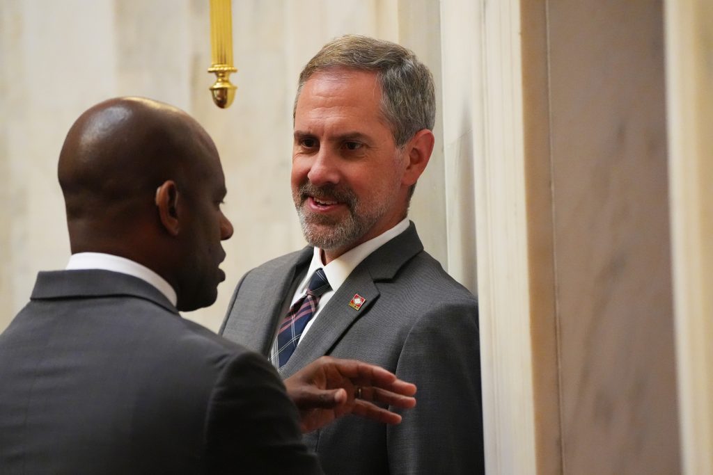 Senator Leding talks with Senator Love in the Senate chamber.