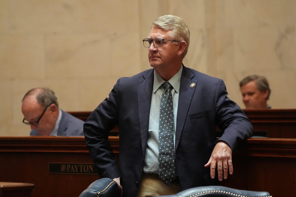 Senator Hill stands at his desk while listening in the Senate chamber