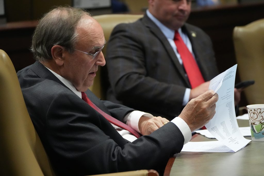 Senator Mark Johnson reads papers at his desk in a committee room