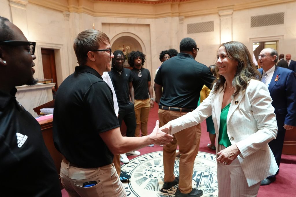 Senator Irvin shakes hands with a high school basketball coach after a presentation on the Senate floor.