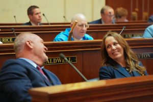 Senators Hickey and Irvin smile at each other while talking in the Senate chamber