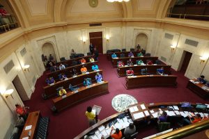 Overhead shot of the Senate chamber taken from a gallery. Boys State delegates are seen at work in various places on the floor.