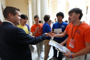 Senator Simon hands out challenge coins to Boys State delegates outside the Senate chamber.