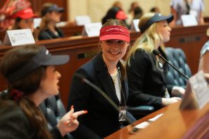 A Girls State senator smiles while talking to fellow delegates in the Senate chamber.