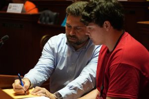 Senator Dismang writes down some notes for a Boys State delegate