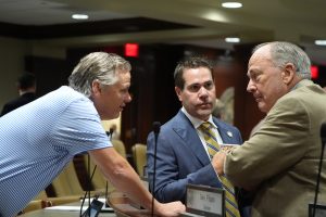 Three senators talk before a committee meeting